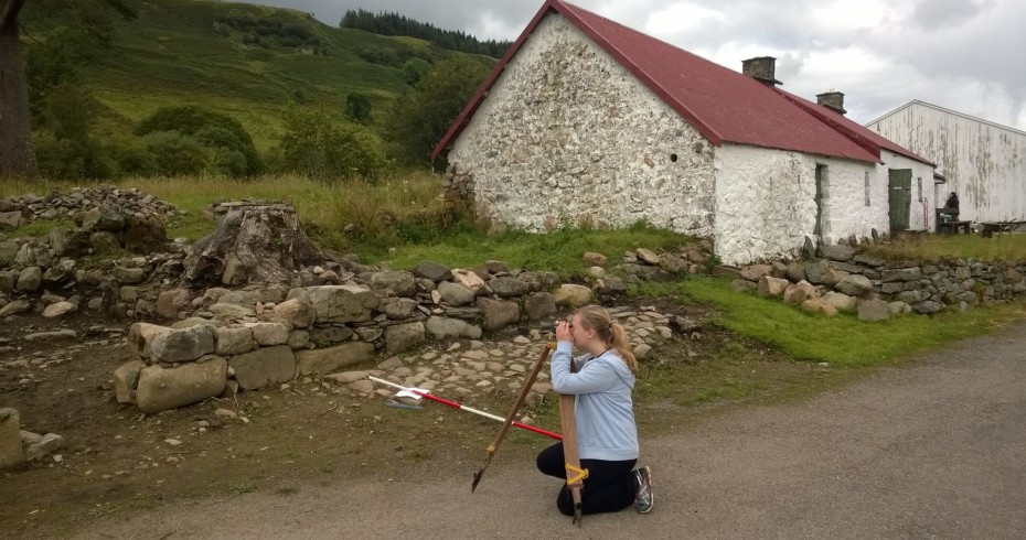 Silja with a surveying level measuring up the site during the excavation work. 