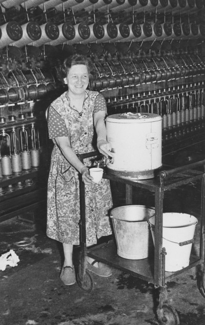 Women serving tea in front of a winding machine image