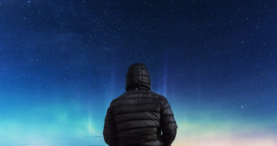 man with back to camera looking up at starlit night sky man with back to camera looking up at starlit night sky