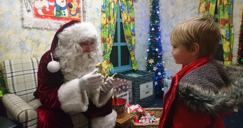 santa in a grotto speaking to a little boy