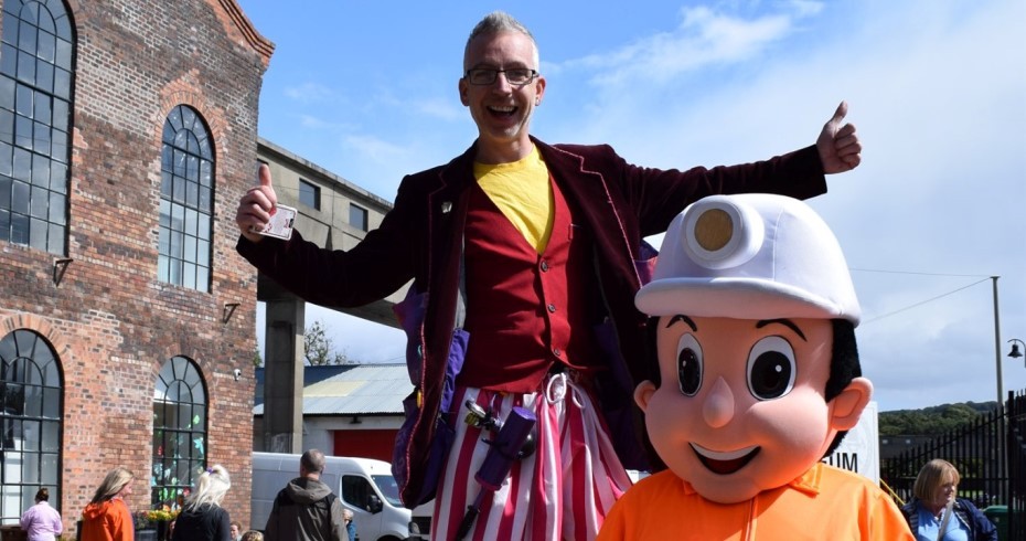 man on stilts and miner character at museum