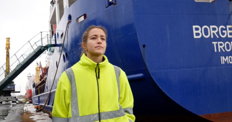 image of woman in safety jacket standing next to huge blue boat