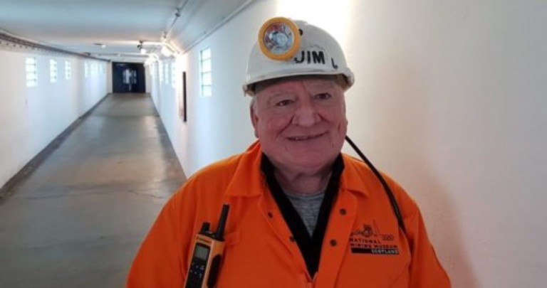 jim lennie tour guide in orange boiler suit wearing pit helmet