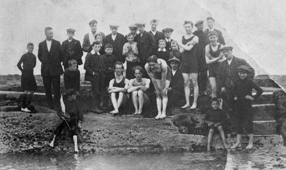 black and white photo of group of men and boys at tidal pool