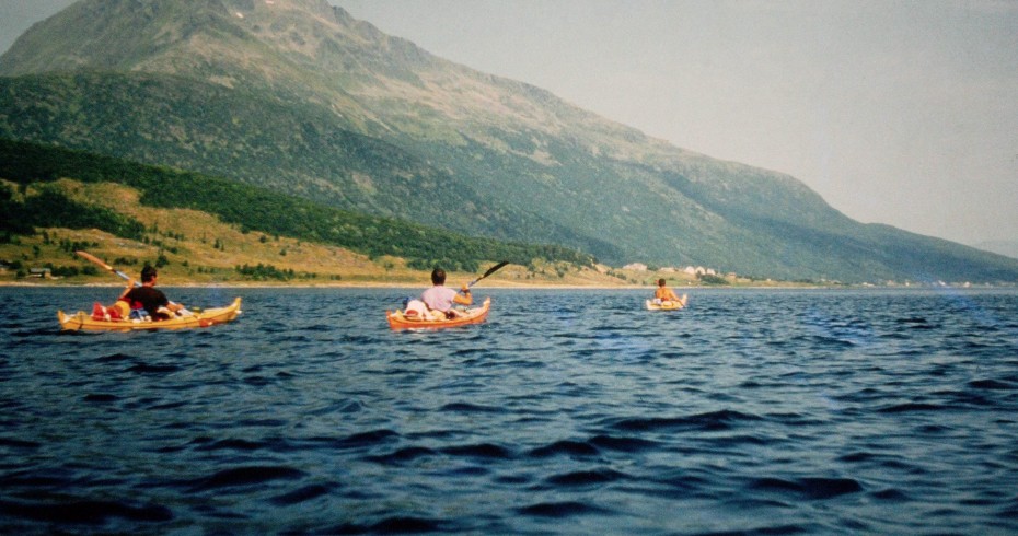 image of three kayaks on blue water with hill in background