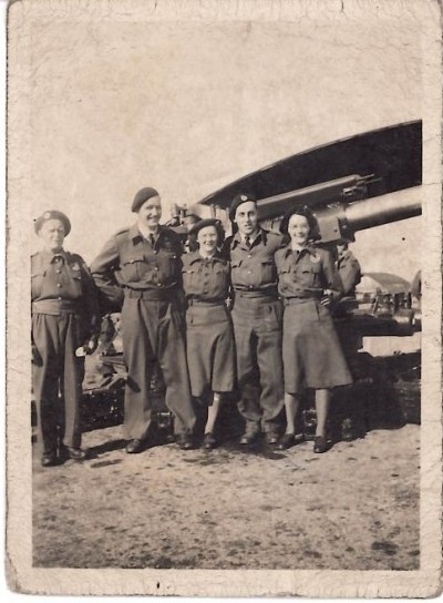 Photograph of men and women in uniform in front of gun image