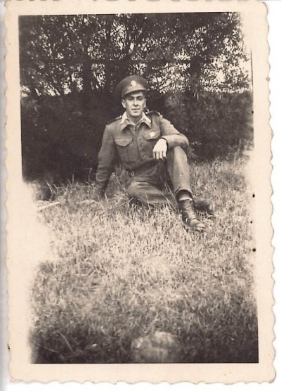Photograph of a man in uniform sat in grass image